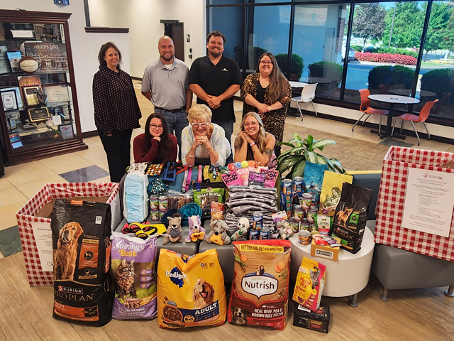 A group of adults with a large donation of dog food, toys and treats for Rescue One.