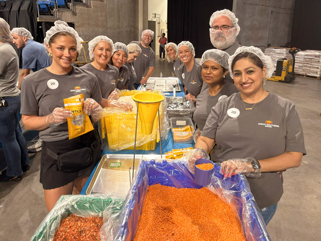 A group of adults assembling shelf stable meals at a large event.