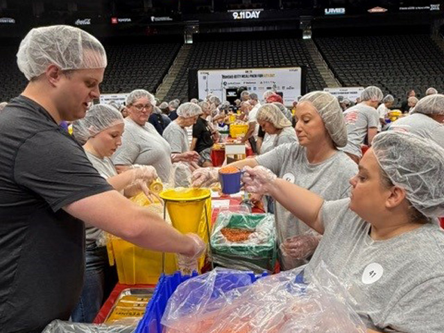 A group of adults pouring ingredients to make shelf stable meals.