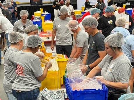 A large group of adults assembling shelf stable meals.